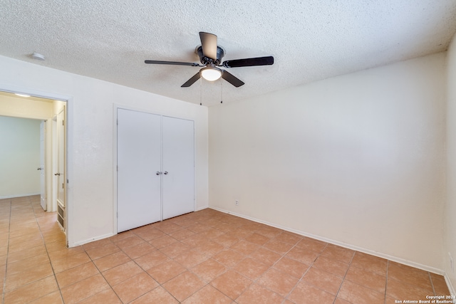 unfurnished bedroom with a closet, ceiling fan, light tile patterned floors, and a textured ceiling