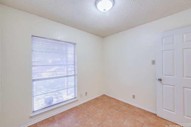 unfurnished room featuring a textured ceiling and light tile patterned floors