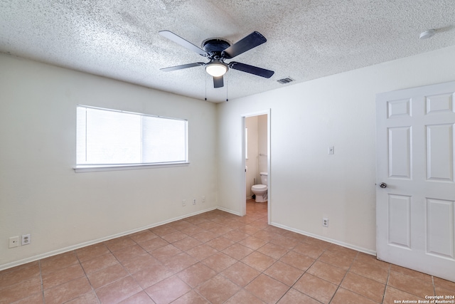 tiled empty room featuring a textured ceiling and ceiling fan