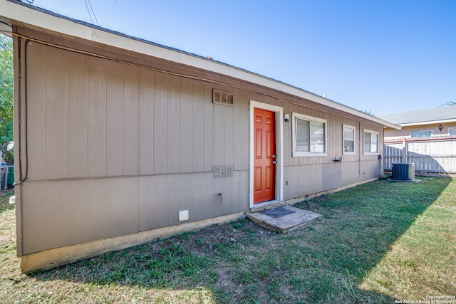 rear view of property featuring a lawn and central air condition unit