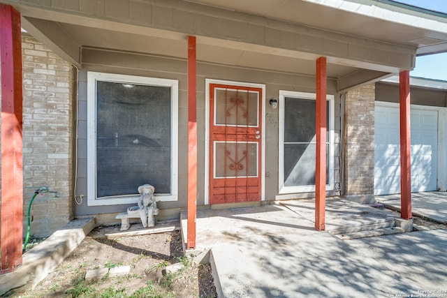 doorway to property featuring covered porch and a garage