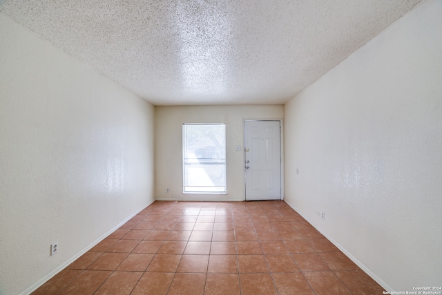 empty room featuring a textured ceiling and light tile patterned floors