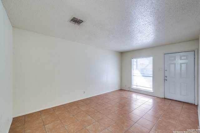 interior space with a textured ceiling and light tile patterned flooring