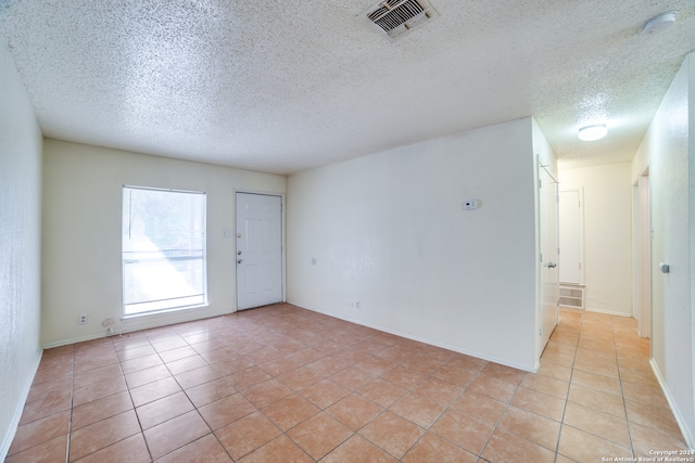 spare room with a textured ceiling and light tile patterned floors