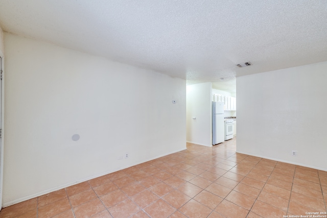 empty room featuring a textured ceiling and light tile patterned floors