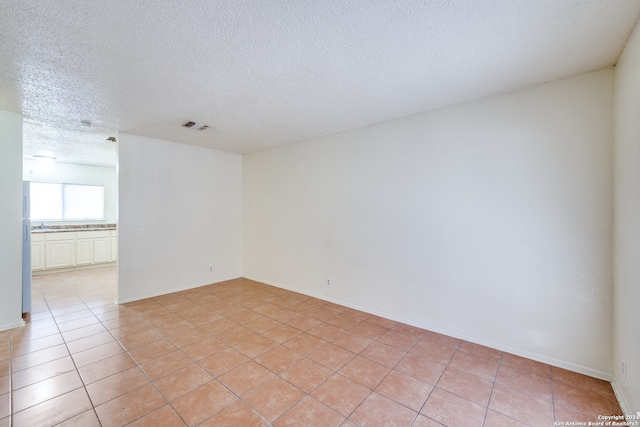 spare room with a textured ceiling and light tile patterned floors