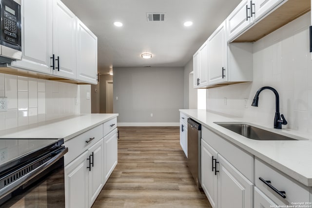 kitchen featuring dishwasher, sink, white cabinets, light hardwood / wood-style flooring, and decorative backsplash