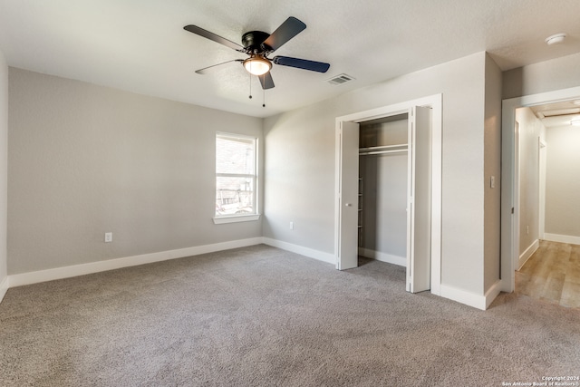 unfurnished bedroom with ceiling fan, light colored carpet, and a closet