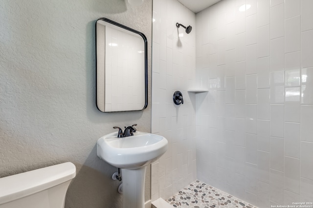 bathroom with tiled shower and toilet