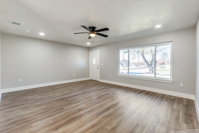 unfurnished room featuring light hardwood / wood-style flooring, ceiling fan, and a textured ceiling