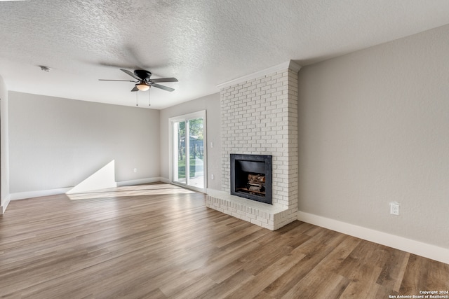 unfurnished living room with ceiling fan, a textured ceiling, a fireplace, and light hardwood / wood-style flooring