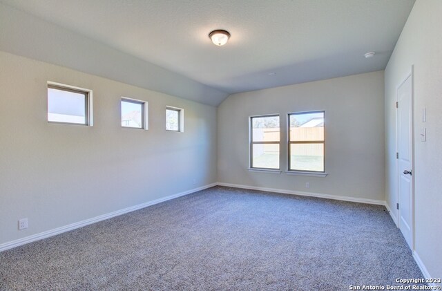 carpeted spare room featuring lofted ceiling