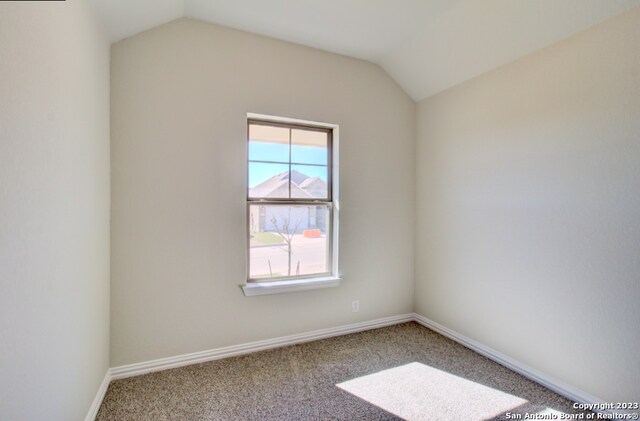 unfurnished room with carpet flooring and vaulted ceiling