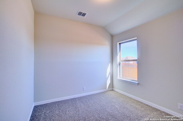 carpeted spare room featuring vaulted ceiling