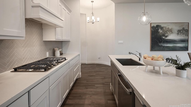 kitchen with custom exhaust hood, appliances with stainless steel finishes, sink, decorative light fixtures, and white cabinets