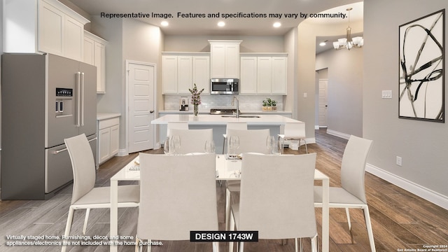 kitchen featuring a kitchen island with sink, white cabinetry, backsplash, appliances with stainless steel finishes, and hardwood / wood-style floors