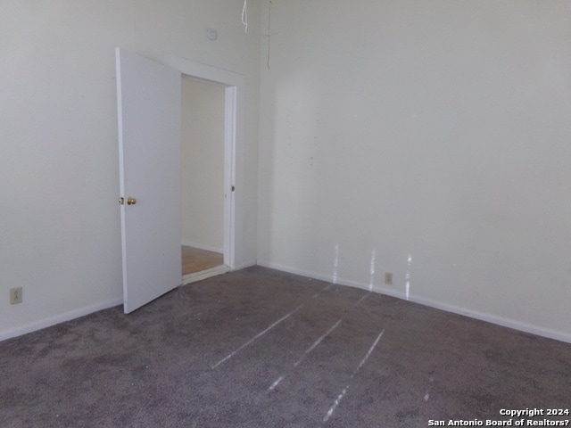 unfurnished room with dark colored carpet