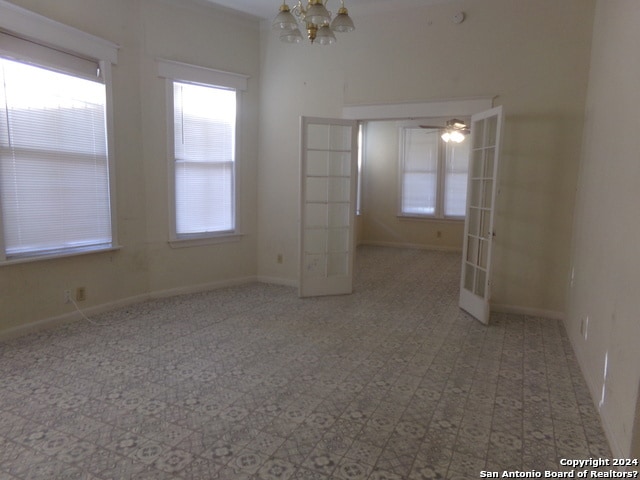 empty room featuring french doors, a chandelier, and a healthy amount of sunlight