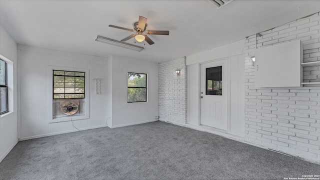 empty room with ceiling fan, brick wall, and carpet flooring