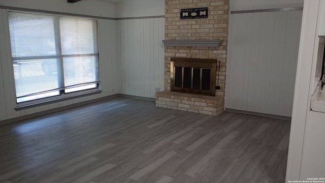 unfurnished living room featuring a fireplace, dark hardwood / wood-style flooring, and wooden walls