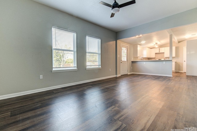 unfurnished living room featuring baseboards, vaulted ceiling, ceiling fan, and dark wood-type flooring