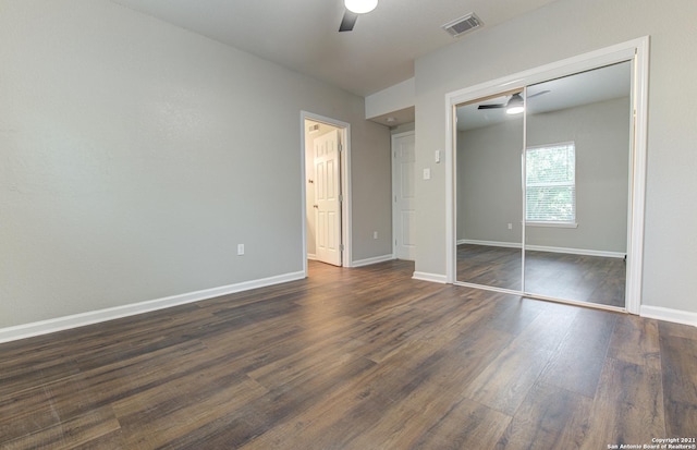 unfurnished bedroom featuring baseboards, dark wood-style floors, visible vents, a ceiling fan, and a closet