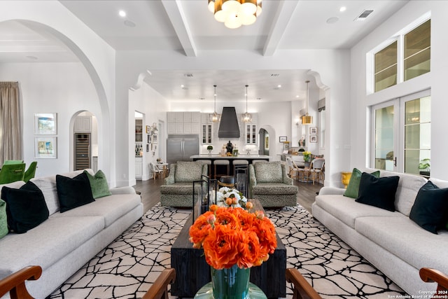 living room with a chandelier, beamed ceiling, hardwood / wood-style flooring, and a healthy amount of sunlight