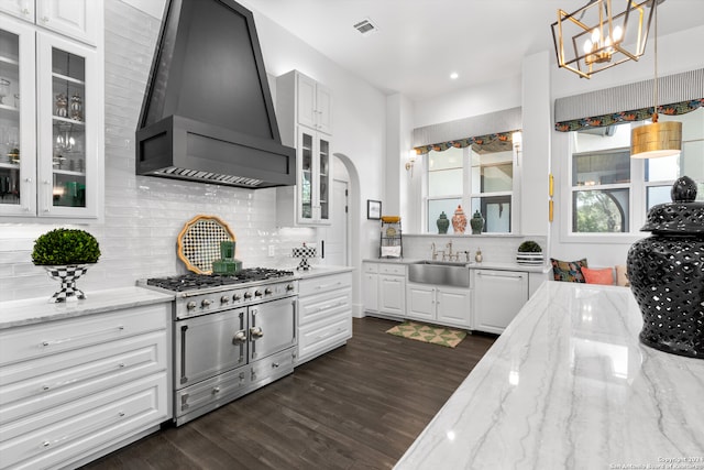 kitchen with decorative light fixtures, custom exhaust hood, light stone countertops, and white cabinetry