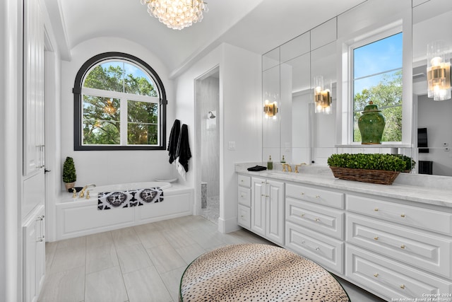 bathroom with a bath, lofted ceiling, vanity, and a chandelier