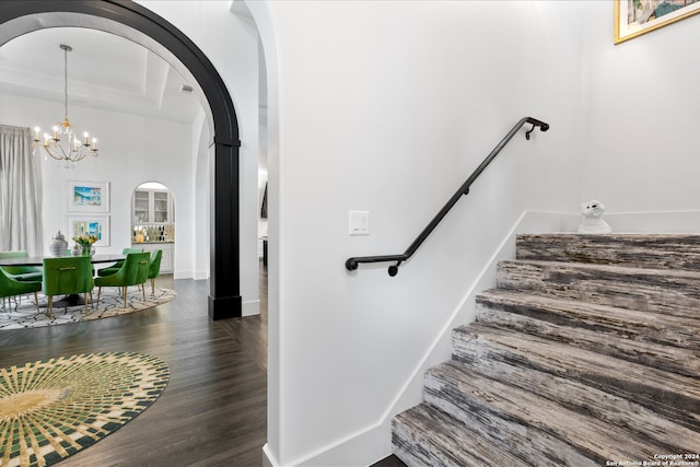 stairway with a notable chandelier, wood-type flooring, and a towering ceiling