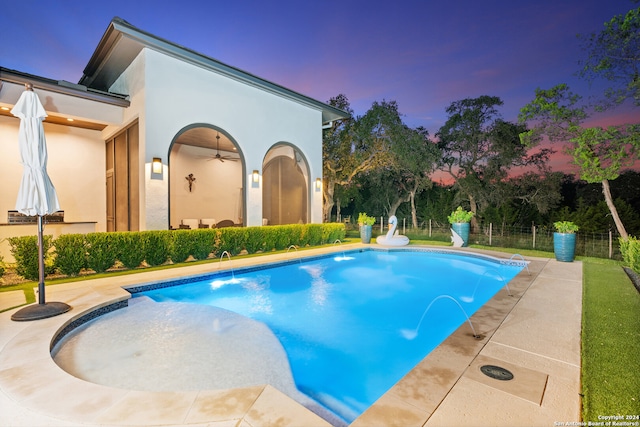 pool at dusk featuring a patio and pool water feature