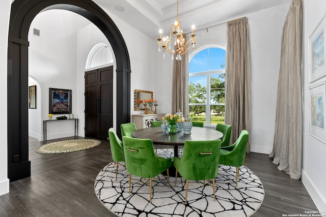 dining area with a towering ceiling, dark hardwood / wood-style floors, and a chandelier