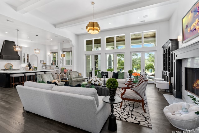 living room featuring beam ceiling, french doors, a premium fireplace, dark wood-type flooring, and an inviting chandelier