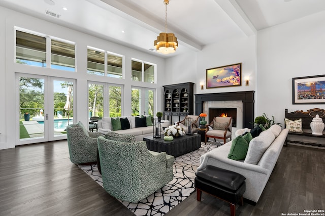 living room featuring wood-type flooring, a chandelier, beamed ceiling, a fireplace, and french doors