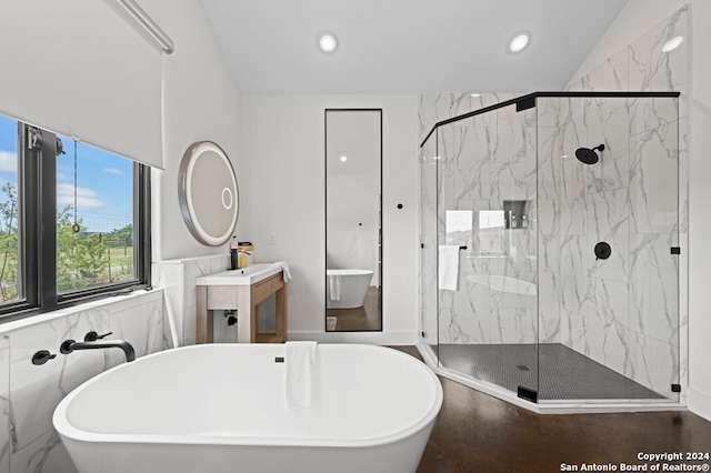 bathroom featuring separate shower and tub, vanity, and tile walls