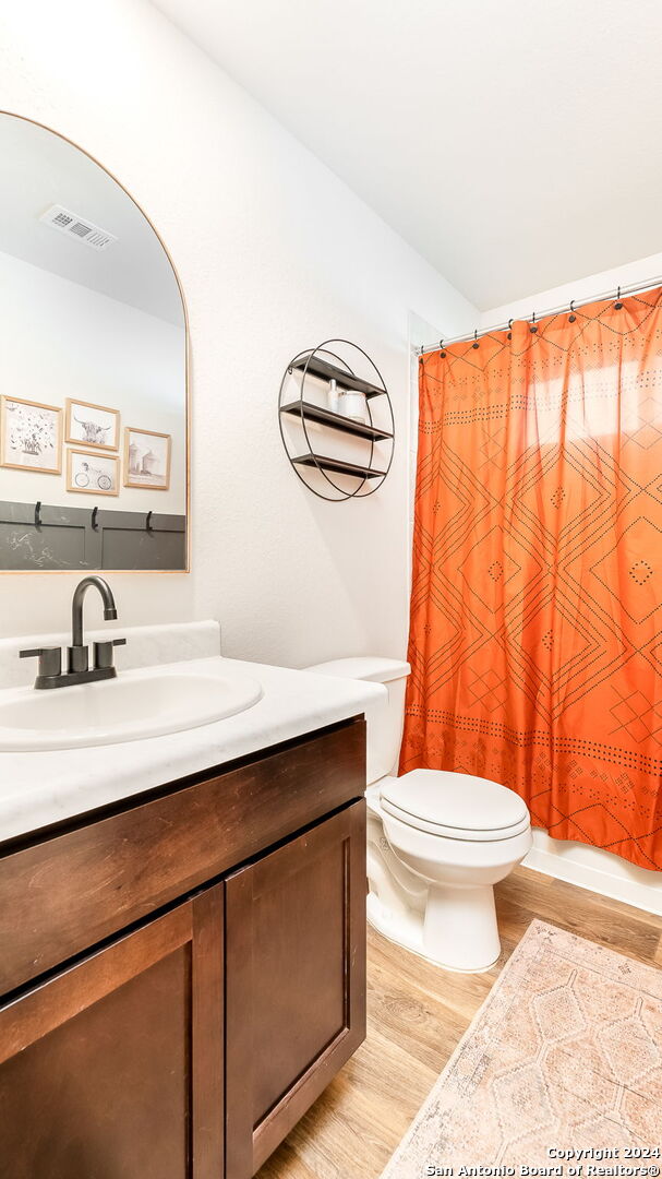 full bathroom with vanity, shower / bath combo with shower curtain, toilet, and hardwood / wood-style flooring