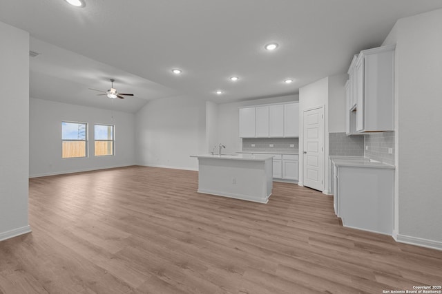 8432 Roadrunner Psge, San Antonio, TX 78222 - kitchen featuring a kitchen island with sink, decorative backsplash, ceiling fan, baseboards, and open floor plan