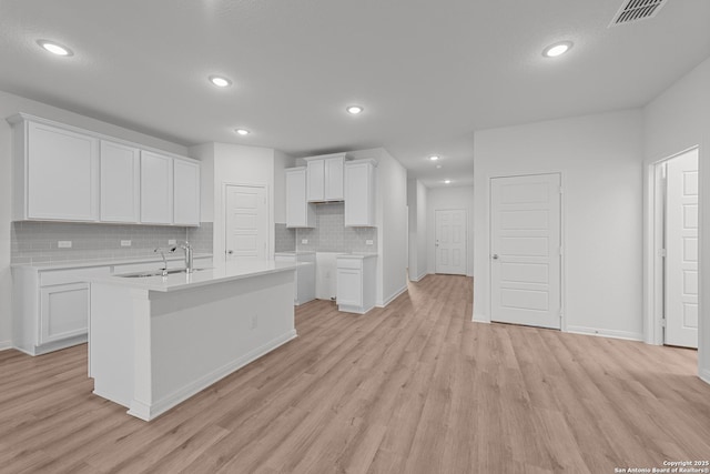 8432 Roadrunner Psge, San Antonio, TX 78222 - kitchen with a sink, light wood-style floors, tasteful backsplash, visible vents, and an island with sink