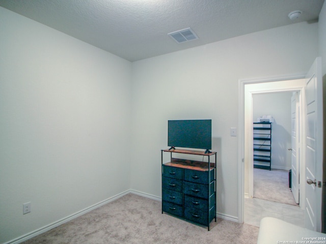 bedroom featuring a textured ceiling and light colored carpet