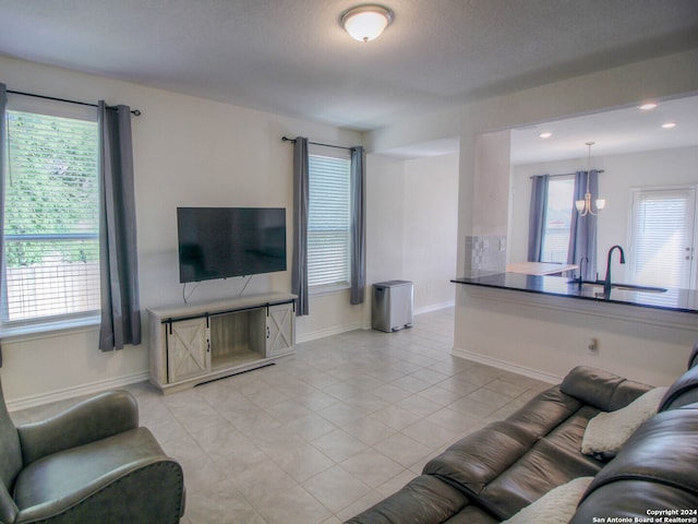 living room with an inviting chandelier, a wealth of natural light, light tile patterned floors, and sink