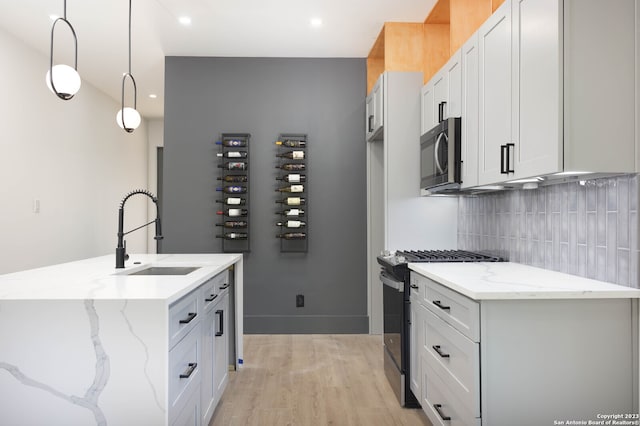 kitchen with light stone countertops, tasteful backsplash, sink, decorative light fixtures, and stainless steel appliances