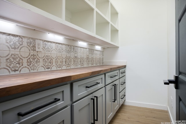 interior space featuring light hardwood / wood-style floors, tasteful backsplash, butcher block counters, and gray cabinetry