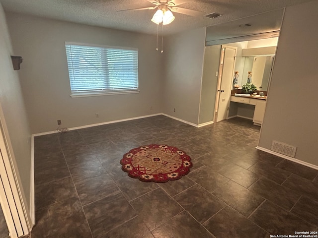 spare room with a textured ceiling, ceiling fan, and built in desk