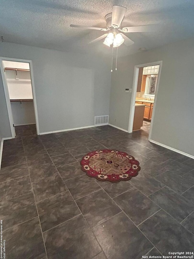 unfurnished room with a textured ceiling and ceiling fan