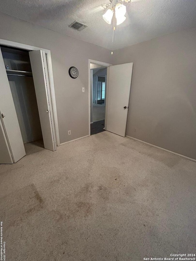 unfurnished bedroom with light colored carpet, a textured ceiling, and a closet