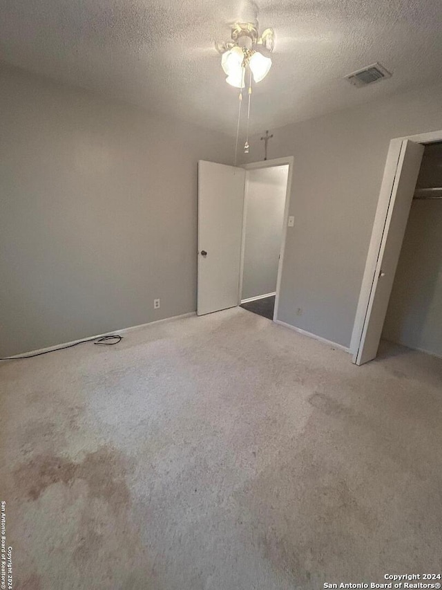 unfurnished bedroom featuring a closet, ceiling fan, a textured ceiling, and carpet flooring