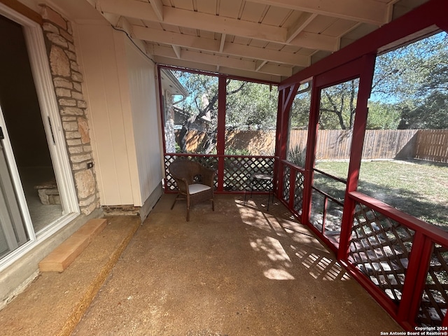 unfurnished sunroom featuring lofted ceiling with beams