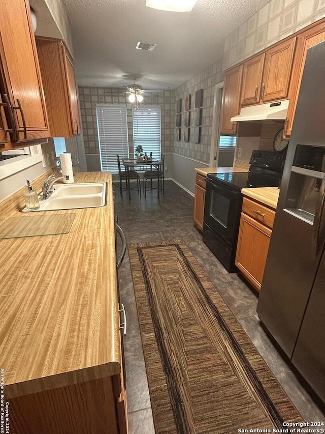 kitchen featuring ceiling fan, black electric range oven, sink, a textured ceiling, and stainless steel fridge with ice dispenser