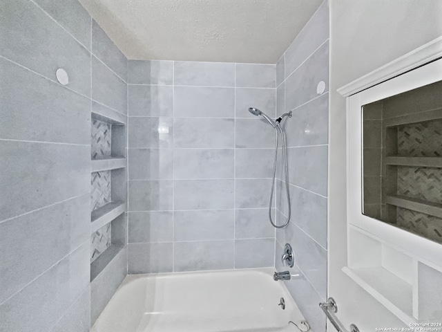 bathroom featuring a textured ceiling and tiled shower / bath combo