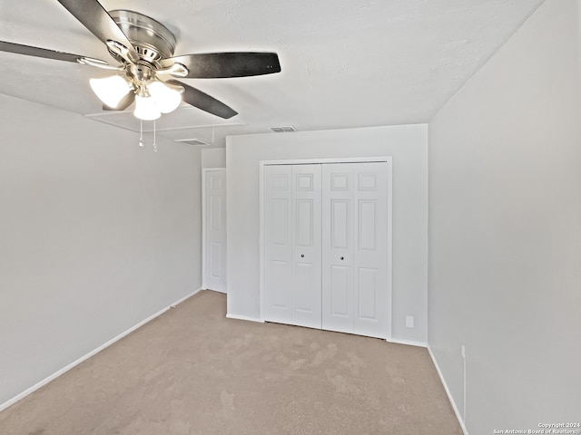 unfurnished bedroom with ceiling fan, light colored carpet, and a closet